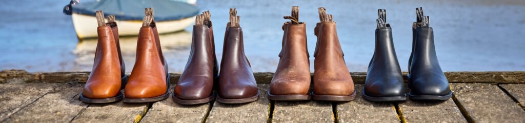 rows of boots on decking with sea in the background