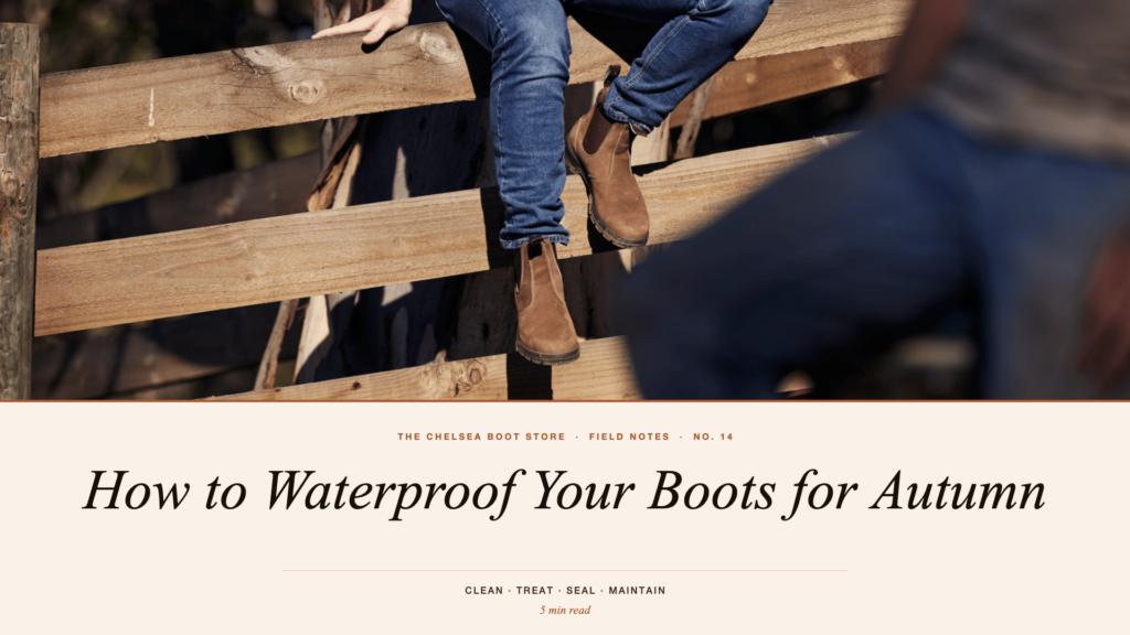 a man sat on a wooden fence in jeans and chelsea boots